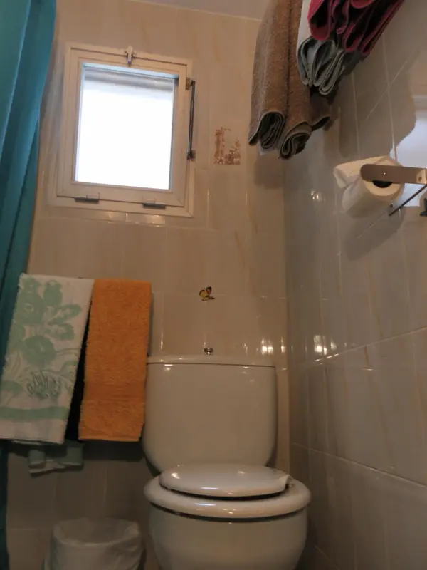 Petite salle de bain carrelée avec des serviettes colorées.