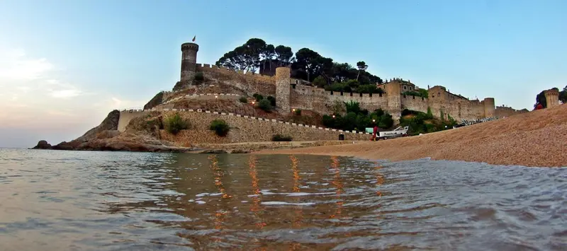Vue d'une forteresse en pierre sur une presqu'île rocheuse bordée par la mer.
