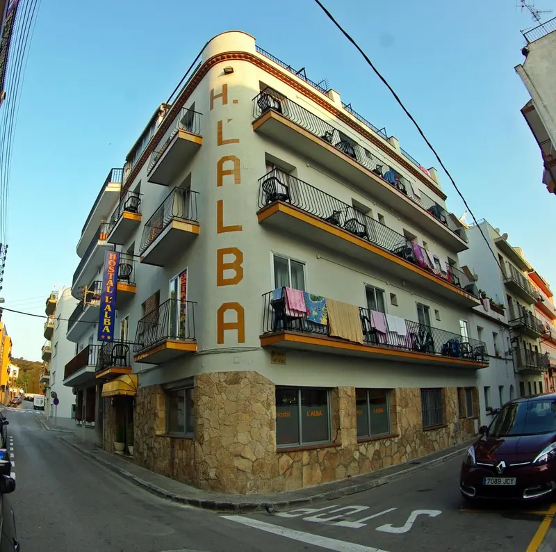 Façade d'un bâtiment d'angle avec des balcons et des fenêtres.