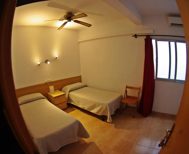 Une chambre simple avec deux lits et une table de chevet.