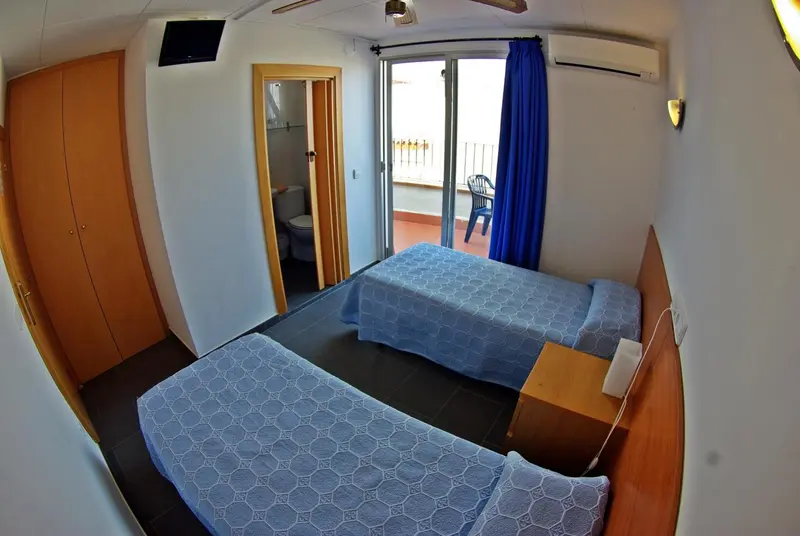 Une chambre lumineuse avec deux lits simples et un accès à une terrasse.