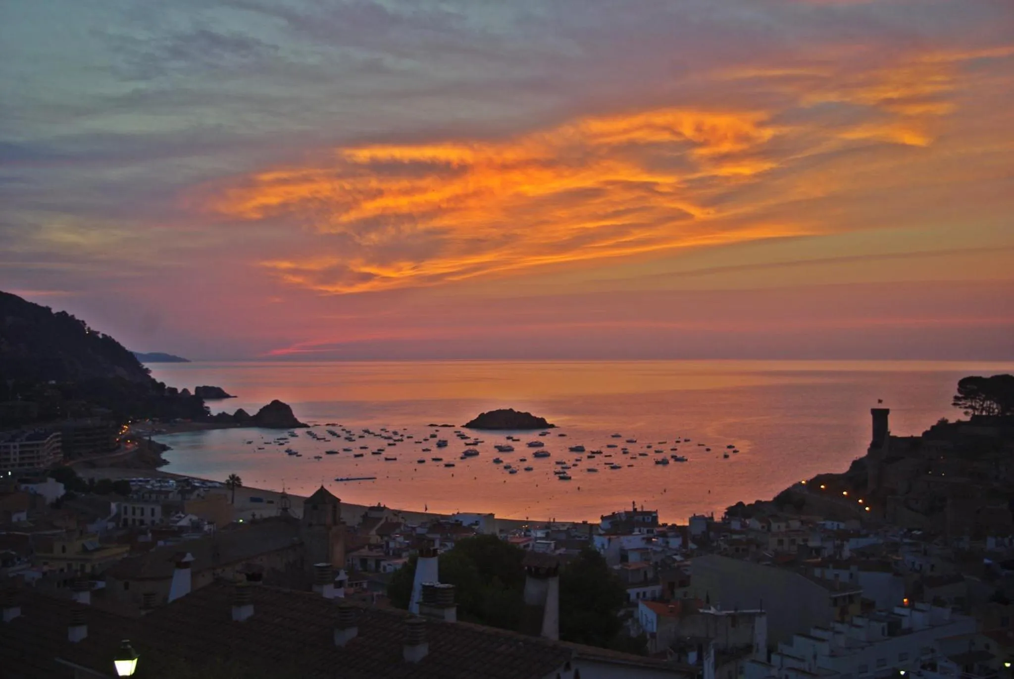 Coucher de soleil sur une baie avec des bateaux amarrés.