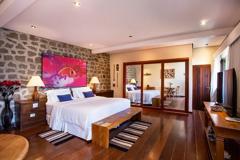 Une chambre lumineuse avec un grand lit et un téléviseur mural.
