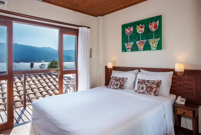 Chambre lumineuse avec un lit double et une vue sur la mer.