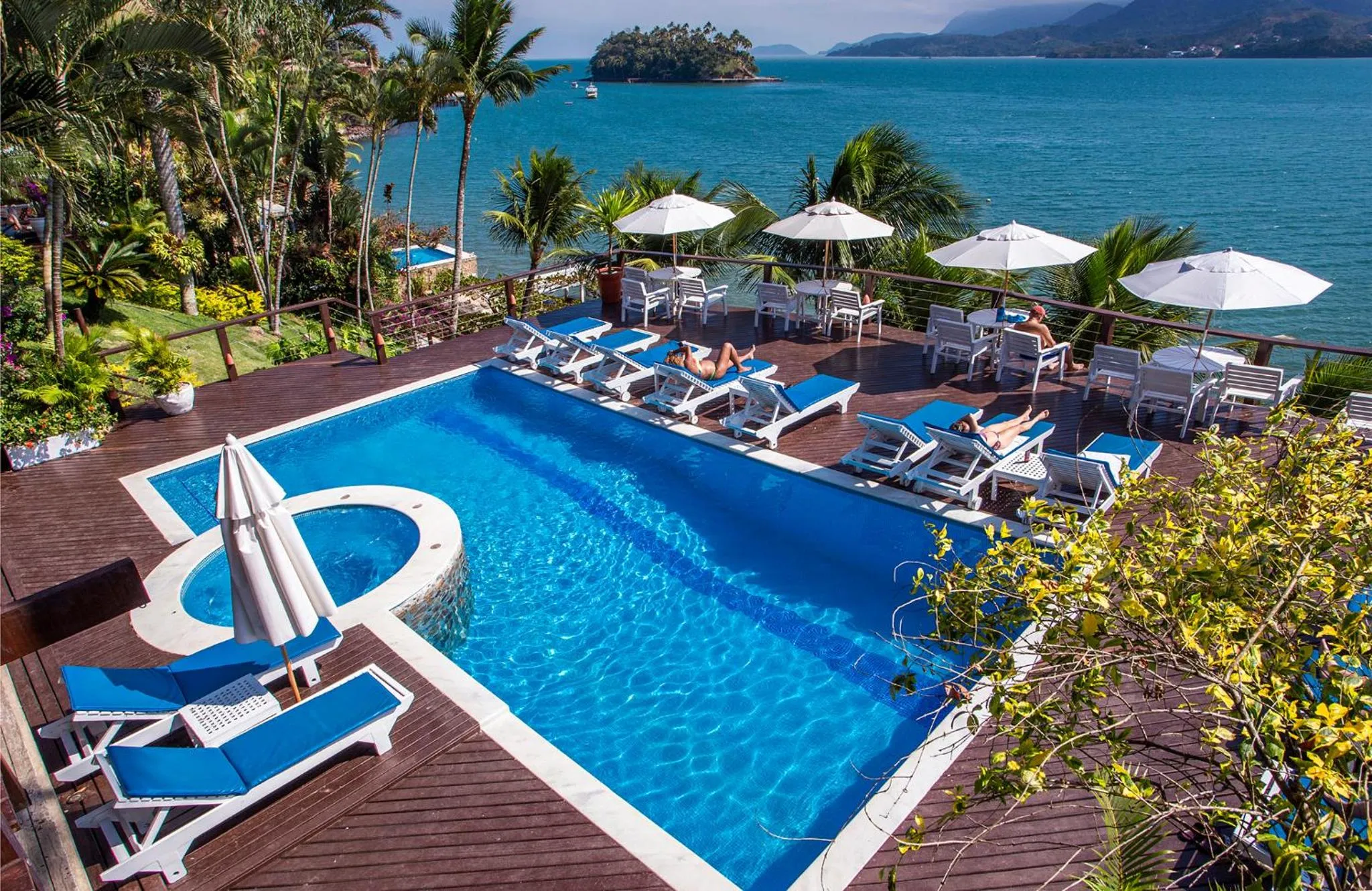 Terrasse avec piscine et transats en bord de mer.