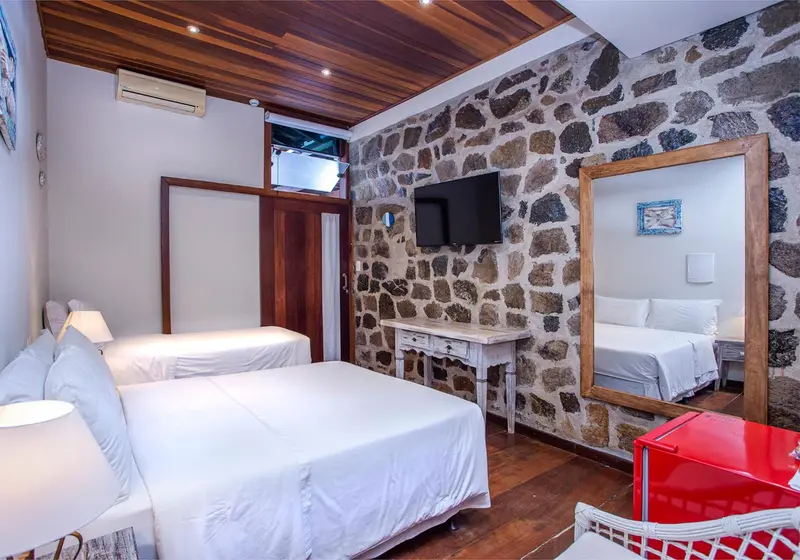 Une chambre lumineuse avec deux lits simples et un mur en pierre.