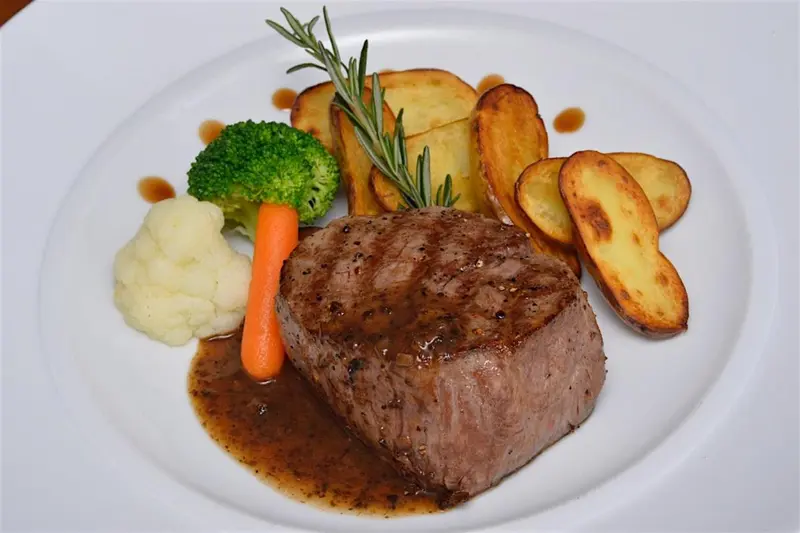 Assiette de viande accompagnée de légumes et de pommes de terre.