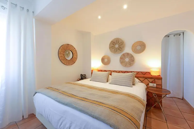 Une chambre lumineuse avec un lit double et des décorations murales en rotin.