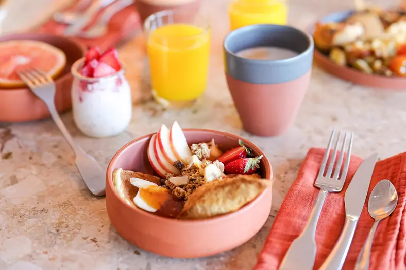 Une table est dressée avec des plats de petit-déjeuner variés et colorés.