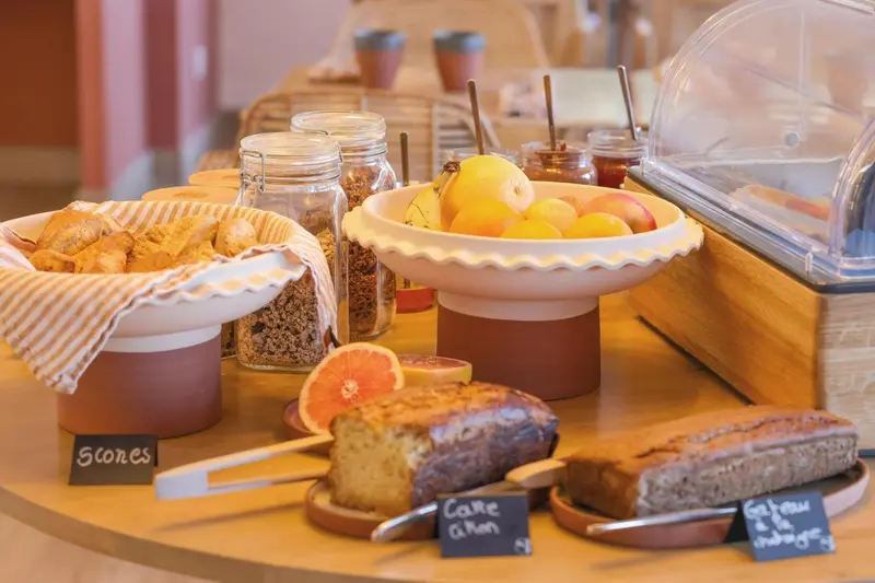 Un buffet propose des viennoiseries, des fruits et des gâteaux.