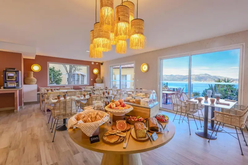 Une salle lumineuse avec un buffet de petit-déjeuner et une vue sur la mer.