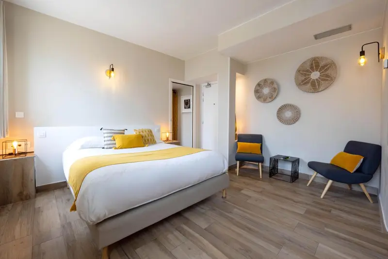 Une chambre lumineuse avec un lit double et un coin salon.
