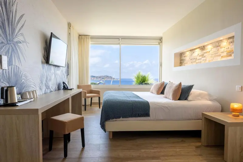 Chambre lumineuse avec un lit double et une vue sur la mer.