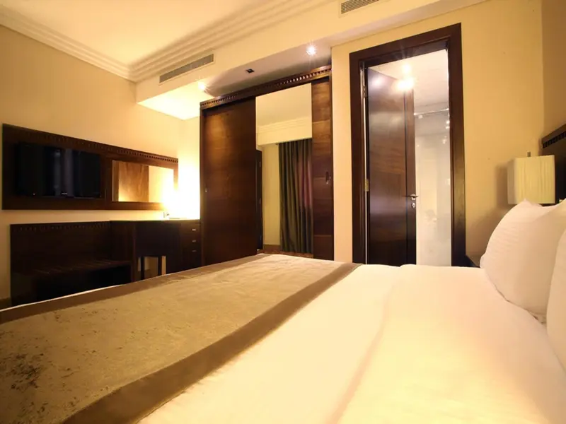 Une chambre d'hôtel lumineuse avec un grand lit et un téléviseur mural.