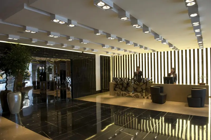 Hall d'entrée moderne avec comptoir d'accueil et sol en marbre noir.
