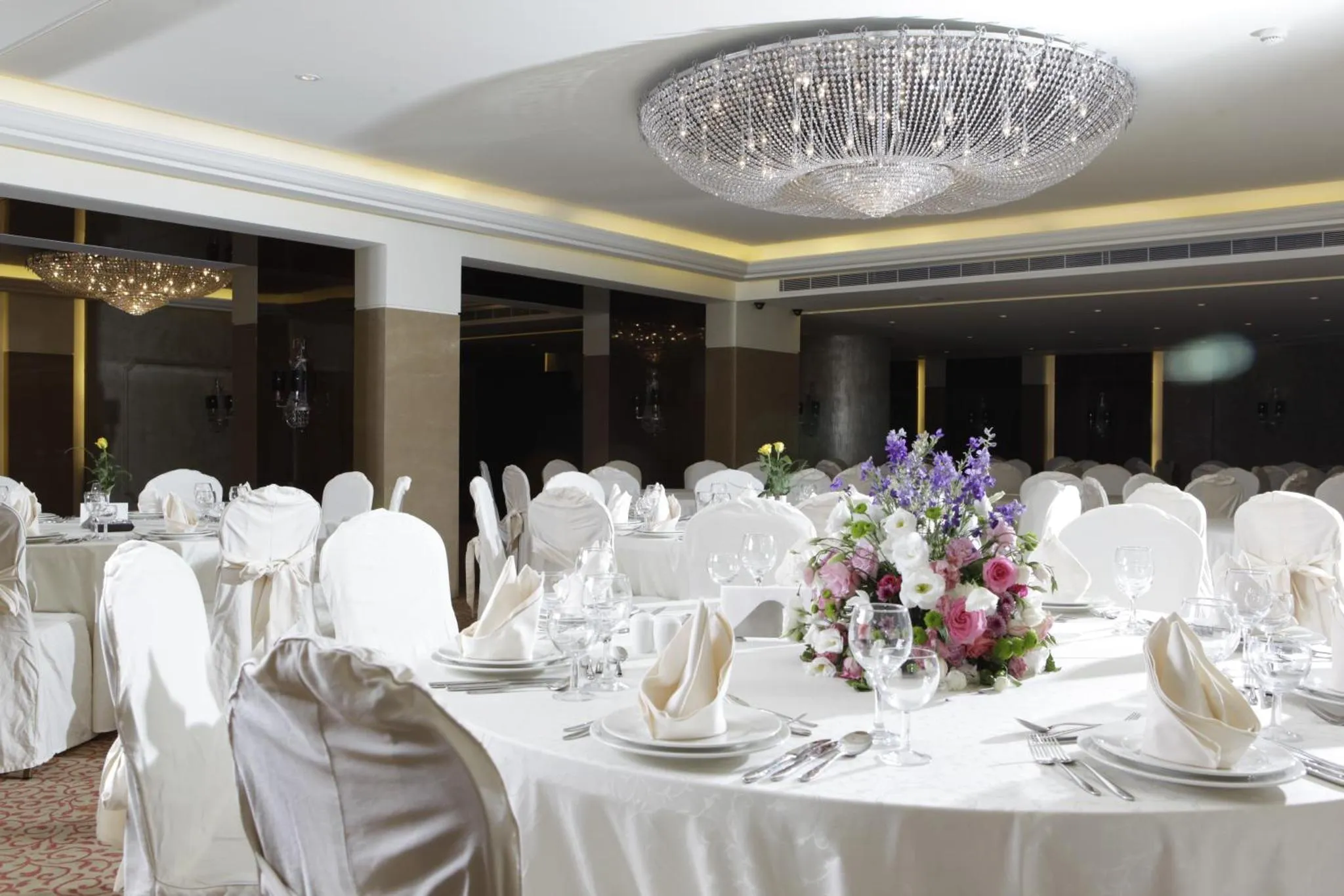 Une salle de réception lumineuse avec des tables dressées pour un banquet.