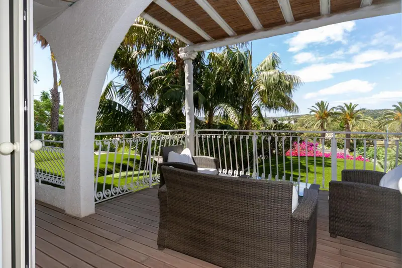 Terrasse ombragée avec mobilier de jardin donnant sur une végétation luxuriante.