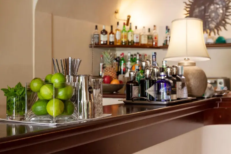 Un comptoir de bar présente des bouteilles, des fruits et des ustensiles.