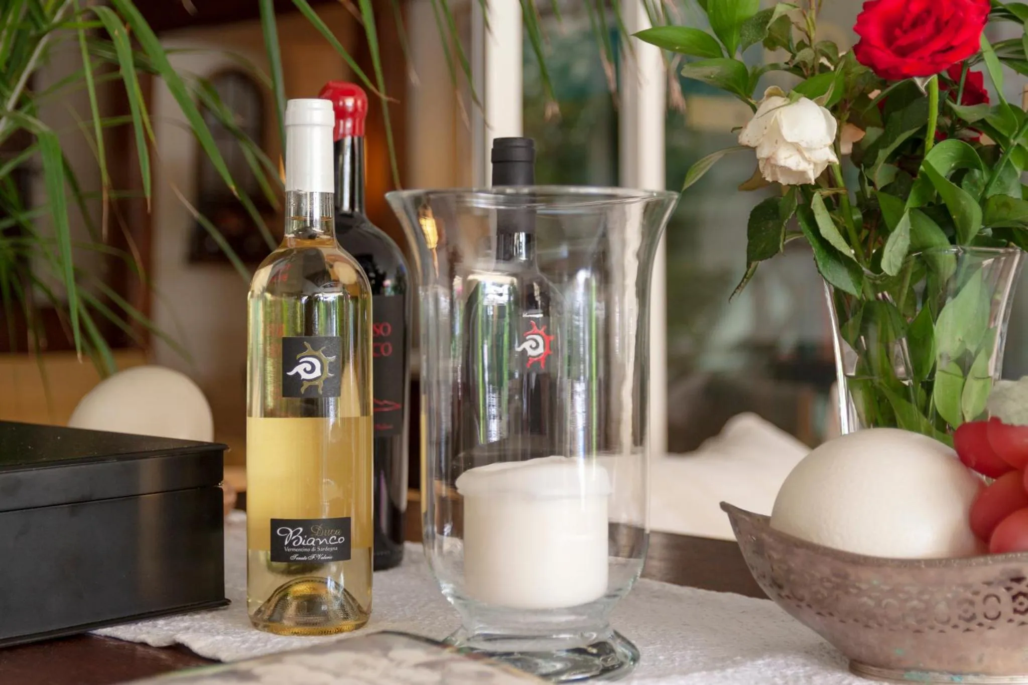 Nature morte avec des bouteilles de vin, des bougies et des fleurs.