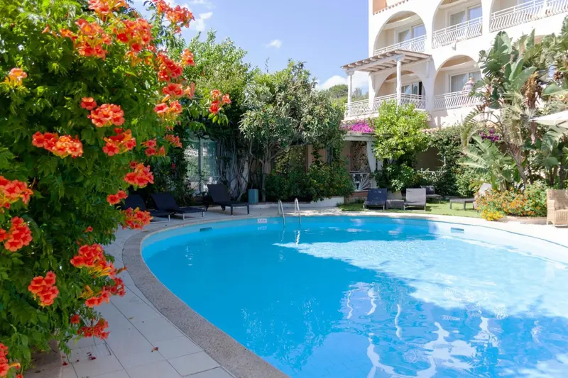 Une piscine rectangulaire bordée de végétation luxuriante et de chaises longues.