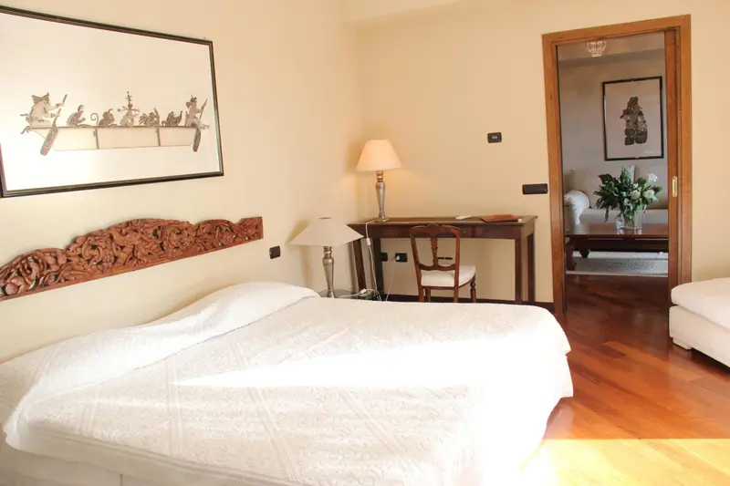 Une chambre lumineuse avec un lit recouvert d'une courtepointe blanche et une décoration murale.