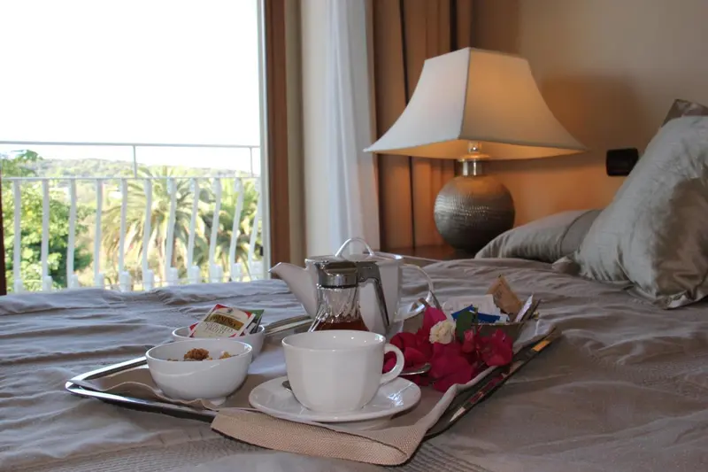 Un petit-déjeuner est servi sur un lit dans une chambre lumineuse.