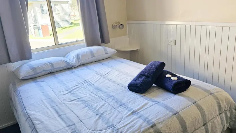 Une chambre lumineuse avec un grand lit recouvert d'une courtepointe blanche et de coussins.