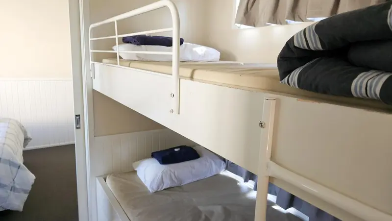 Lits superposés avec oreillers et couvertures pliées dans une chambre.