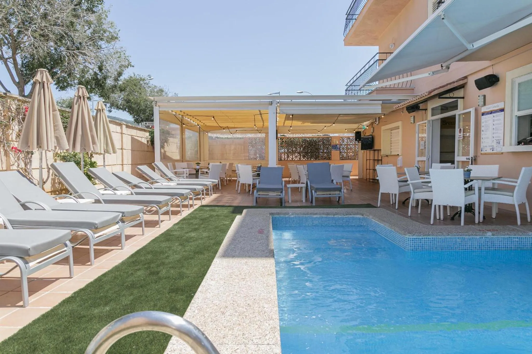 Terrasse ombragée avec transats et petite piscine en bordure de pelouse.