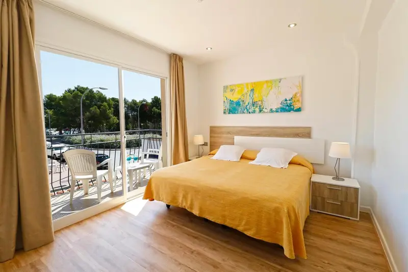 Chambre lumineuse avec un grand lit et un accès à une terrasse.