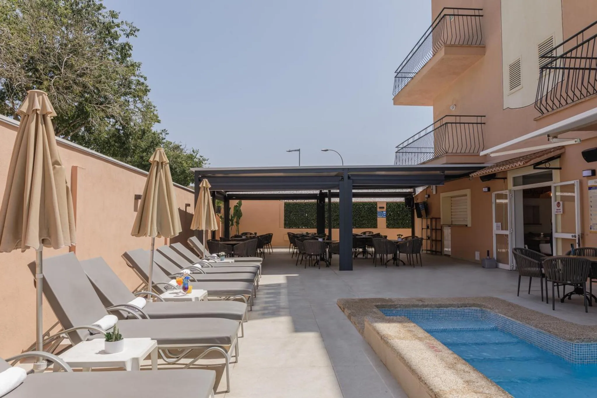 Terrasse ombragée avec transats et petite piscine.