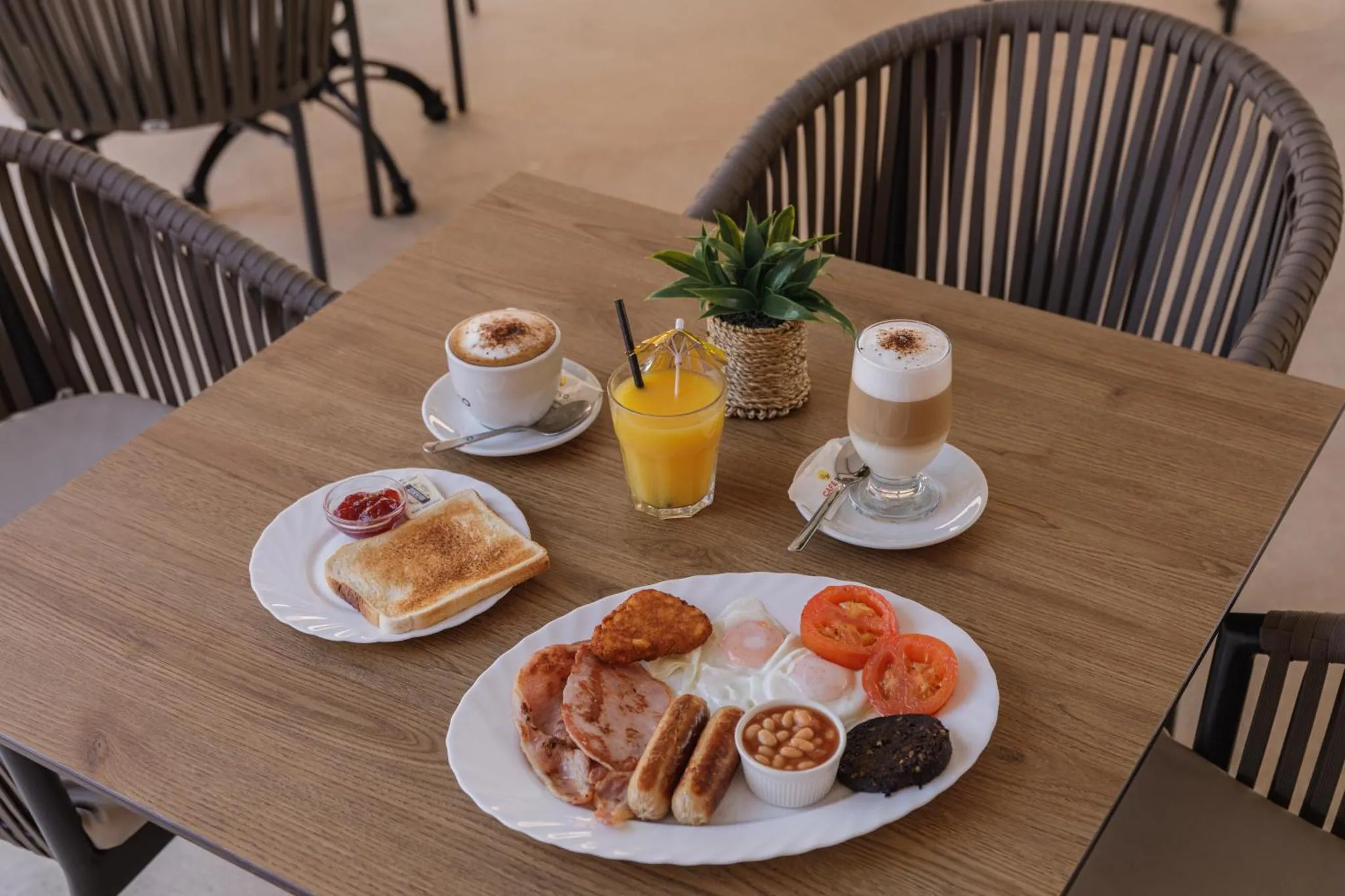 Une table en bois présente un petit-déjeuner copieux avec des boissons et des plats variés.