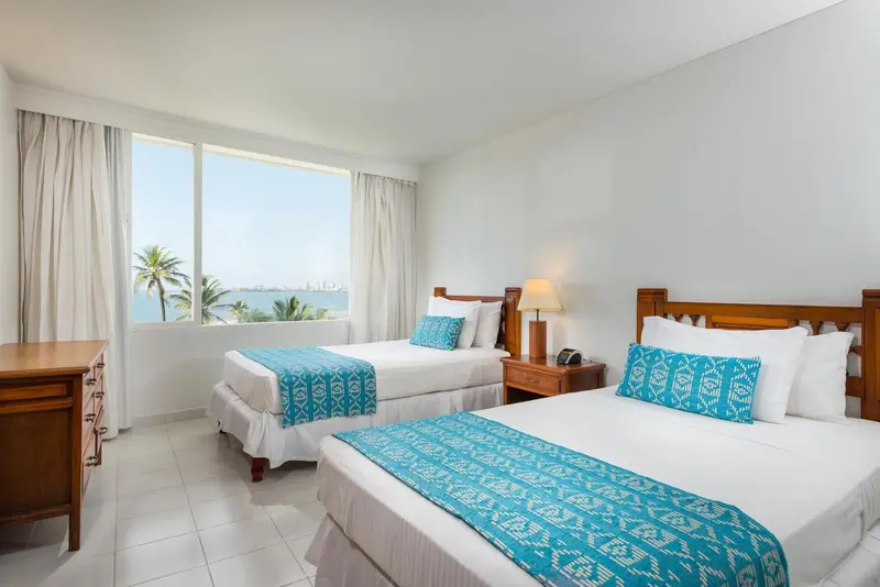 Chambre lumineuse avec deux lits simples et vue sur la mer.