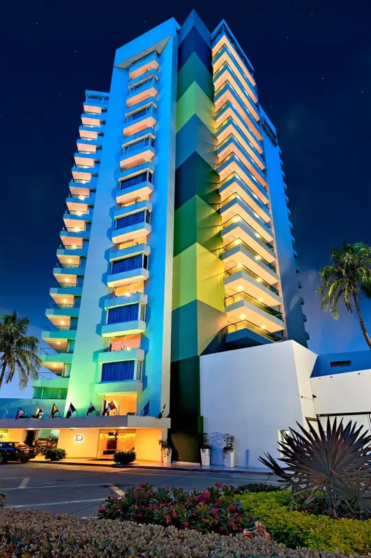 Imposant bâtiment illuminé avec de nombreuses terrasses et balcons.