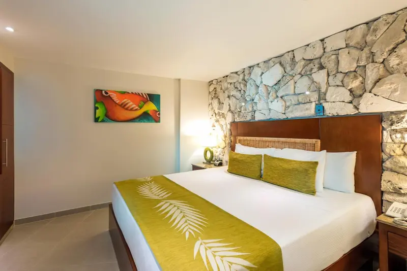 Une chambre lumineuse avec un grand lit et un mur en pierre.