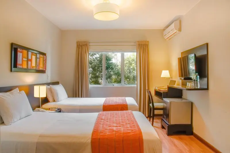 Une chambre avec deux lits simples et un bureau près de la fenêtre.