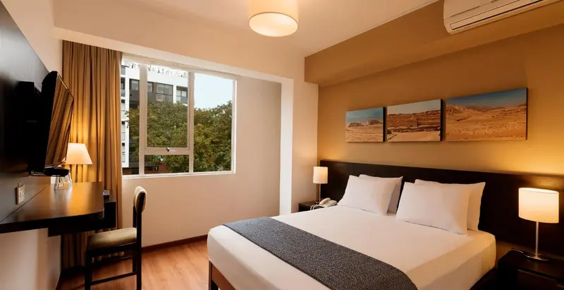 Une chambre d'hôtel lumineuse avec un lit double et un bureau.