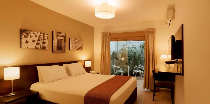 Une chambre lumineuse avec un grand lit et un accès à une terrasse.