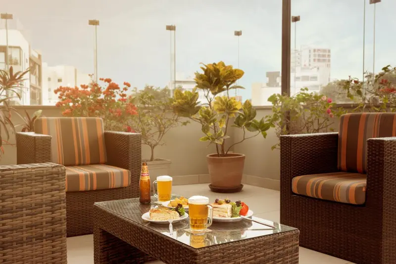 Une table basse avec des boissons et une pâtisserie sur une terrasse aménagée avec des fauteuils en rotin.