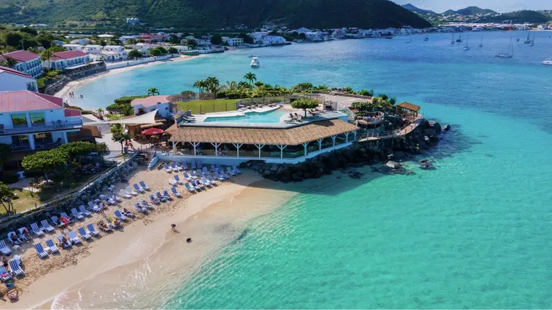 Vue aérienne d'une plage avec des transats et une piscine bordée d'une terrasse.