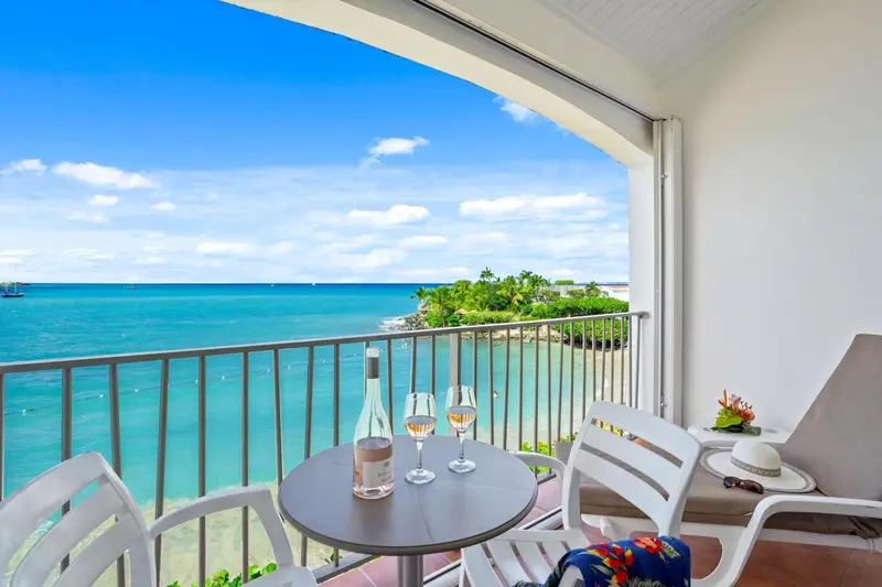 Une table ronde avec des verres et des bouteilles sur une terrasse ensoleillée avec vue sur la mer.