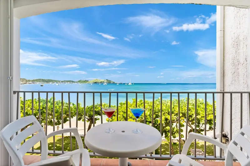 Vue sur la mer depuis un balcon avec une table et des chaises.