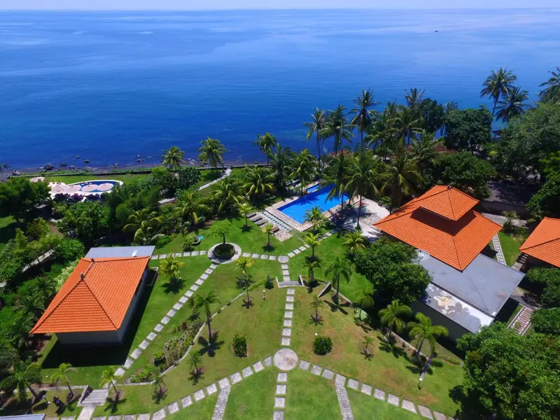 Vue aérienne d'un complexe hôtelier tropical avec piscine et végétation luxuriante.
