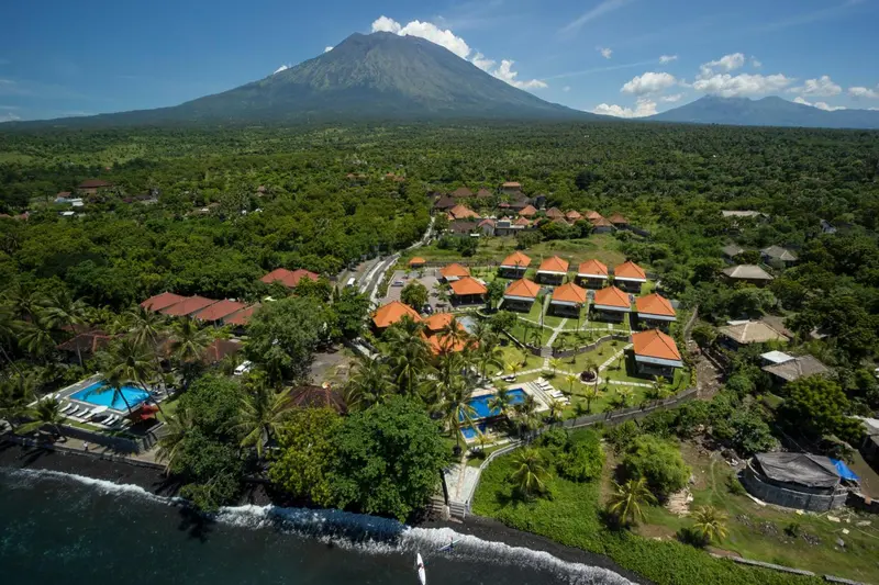 Vue aérienne d'un complexe hôtelier tropical avec piscine et végétation luxuriante.