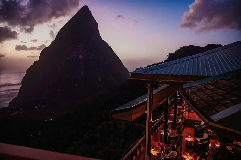 Vue sur une montagne escarpée au coucher du soleil depuis une terrasse éclairée.