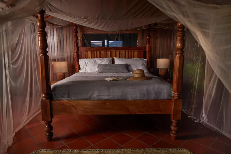 Un lit avec moustiquaire dans une chambre aux tons chauds.