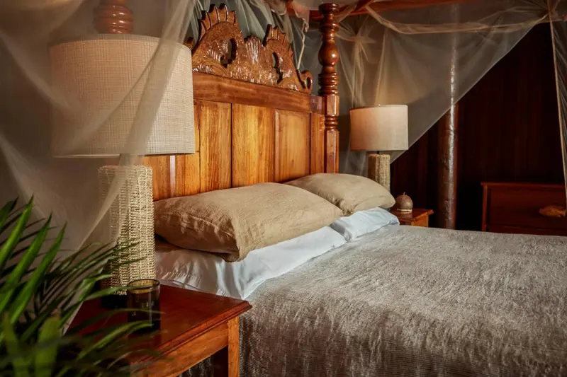 Un lit avec une tête de lit en bois sculpté et une moustiquaire.
