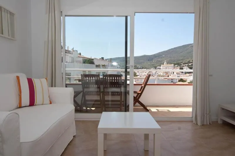 Un salon lumineux s'ouvre sur une terrasse avec vue sur un paysage montagneux.