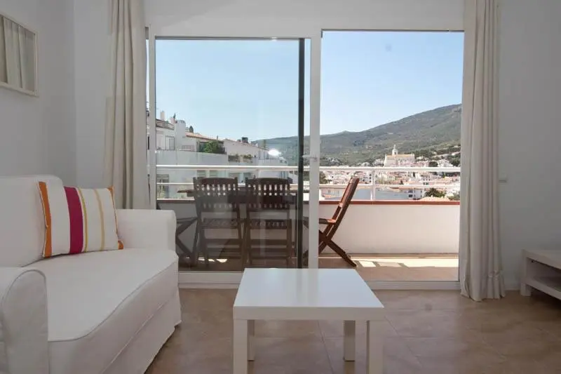 Un salon lumineux s'ouvre sur une terrasse avec vue sur un paysage montagneux.