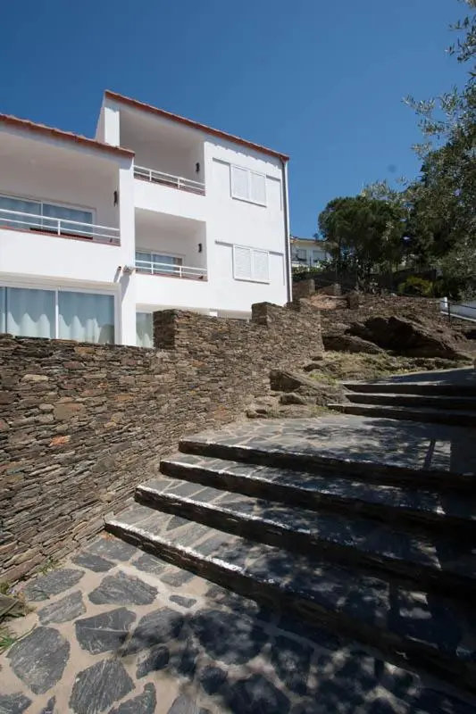 Bâtiment blanc avec des terrasses et un escalier en pierre.